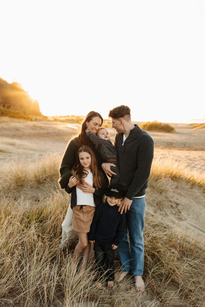 A family of five posing for the camera during their family photoshoot at a well known christchurch beach while being photographed by lucy jane photography a professional photographer in new zealand